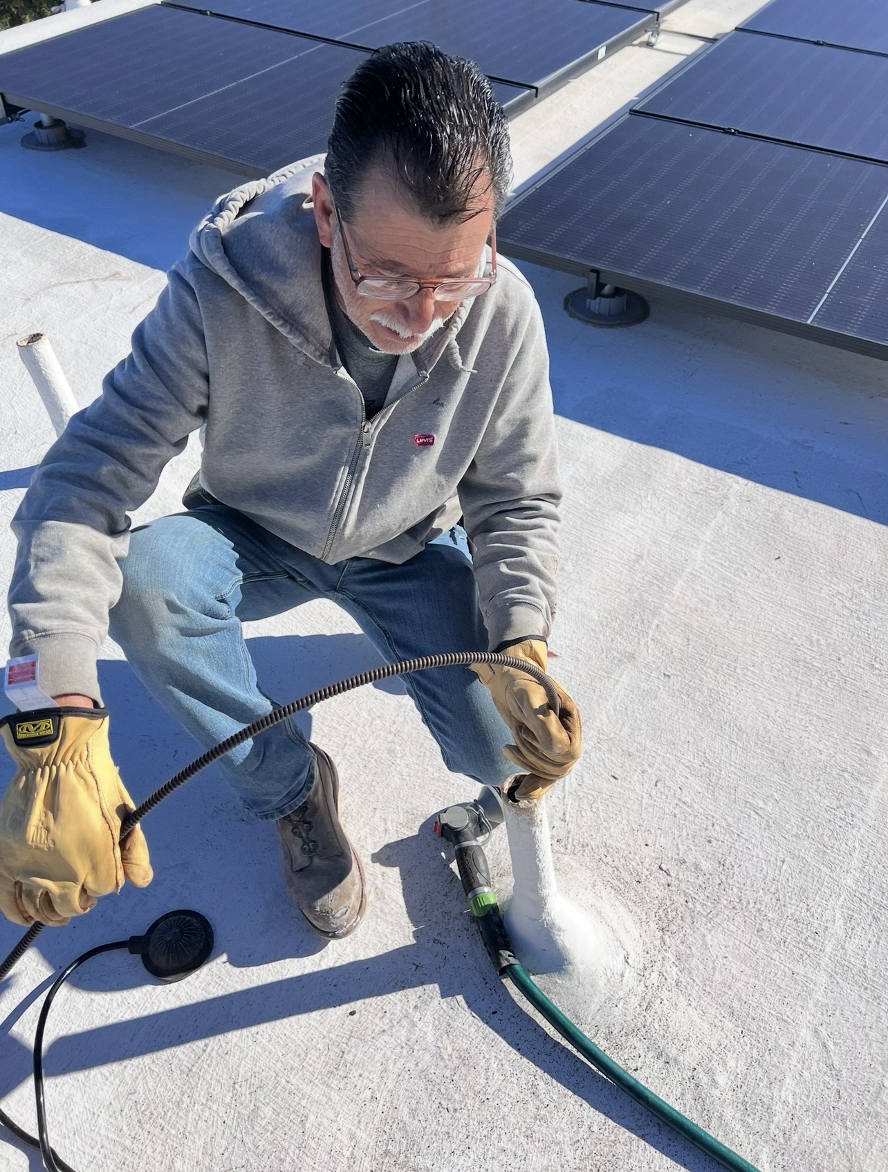 Plumber running a drain cable through a roof vent cleanout